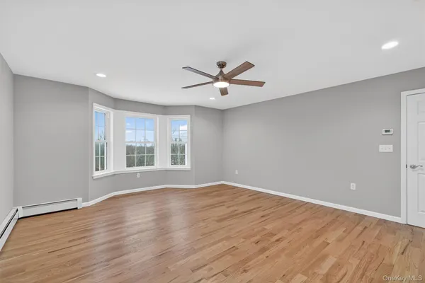 a view of an empty room with a window and wooden floor