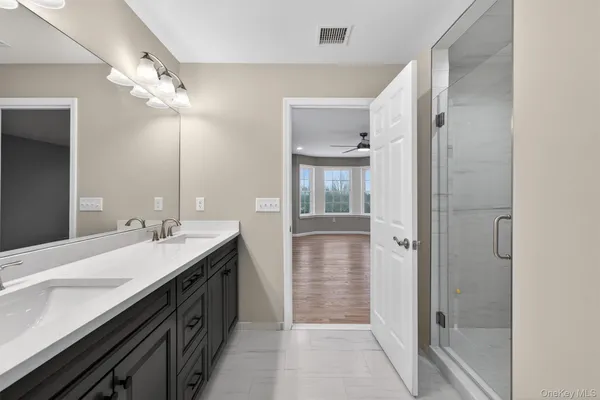 a spacious bathroom with a double vanity sink a mirror and shower