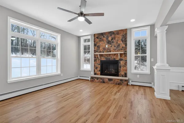an empty room with wooden floor fireplace and windows