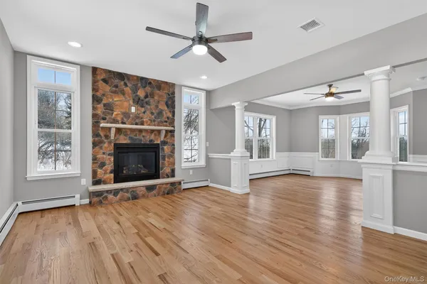a view of an empty room with wooden floor fireplace and a window