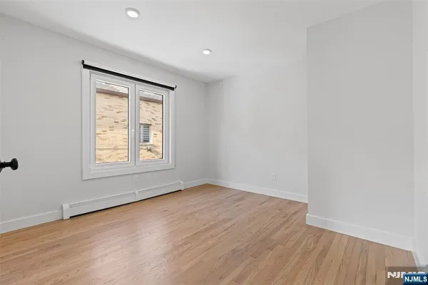 a view of an empty room with wooden floor and closet