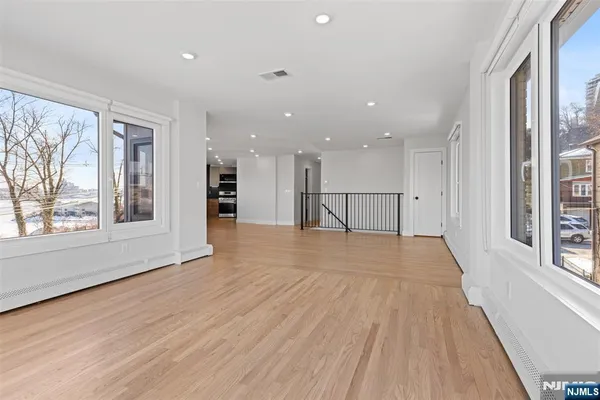 a view of empty room with wooden floor and windows