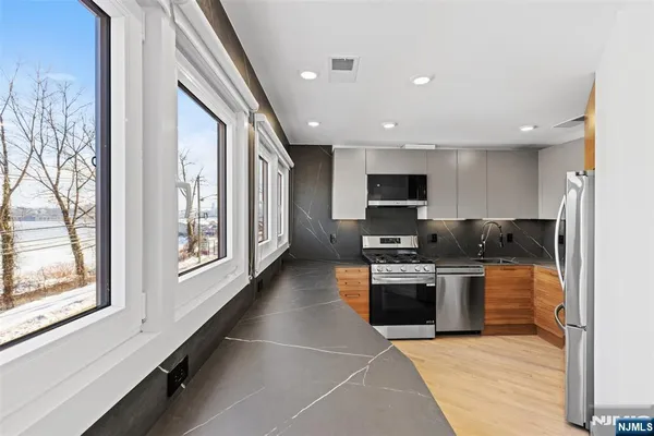 a large kitchen with stainless steel appliances granite countertop a stove and a sink