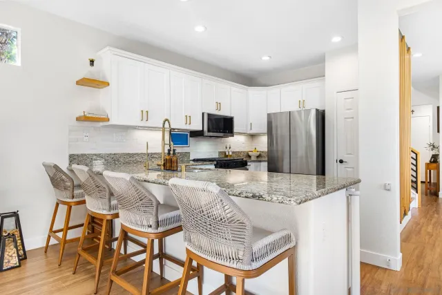 a kitchen with stainless steel appliances granite countertop a stove a refrigerator a sink a dining table and chairs