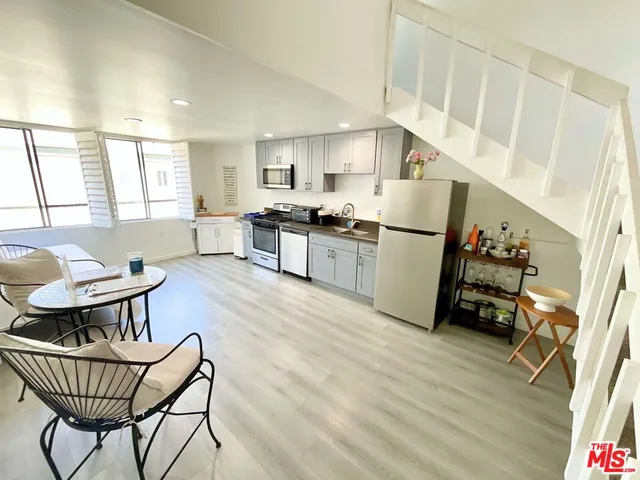 a kitchen with stainless steel appliances a refrigerator a sink a stove a dining table and chairs