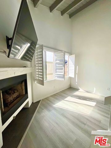 a view of an empty room with wooden floor fireplace and a window
