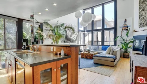 a living room with furniture kitchen view and large windows