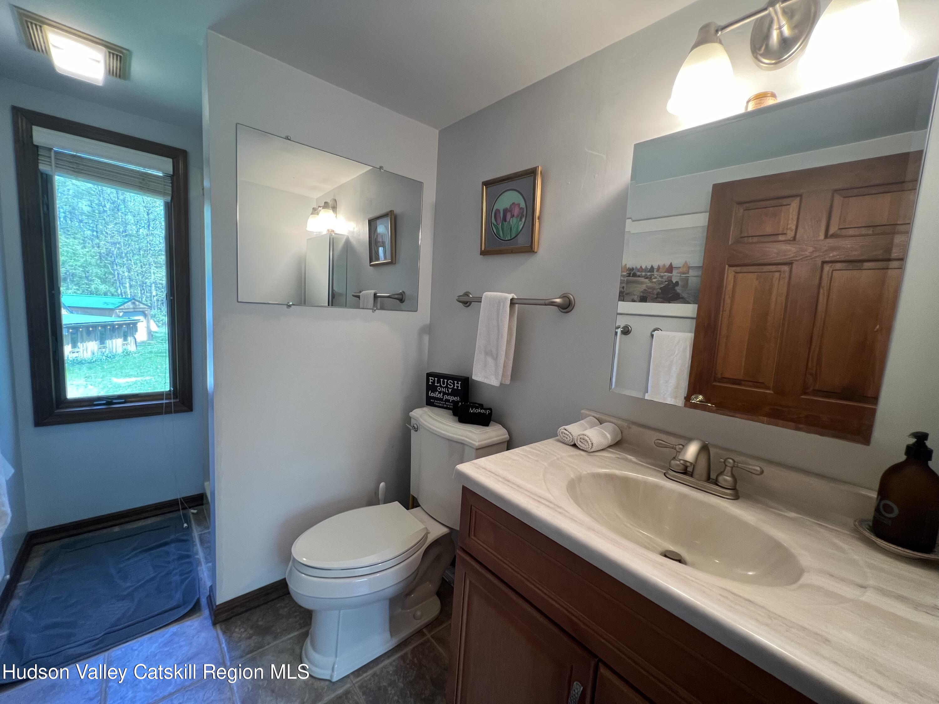 978 Scott Greene Road Roxbury, NY 12474 - Photo 26 of 41 a bathroom with a granite countertop sink toilet and mirror