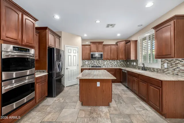a kitchen with kitchen island granite countertop wooden cabinets stainless steel appliances and a granite counter tops