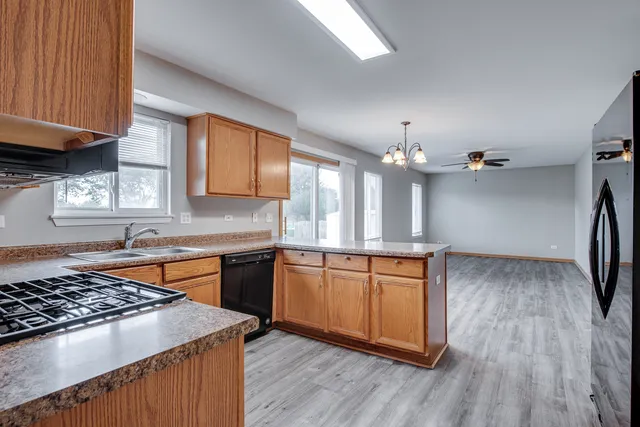 a kitchen with stainless steel appliances granite countertop a stove a sink dishwasher and a refrigerator with wooden floor