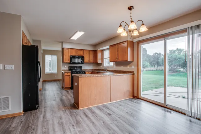 a kitchen with stainless steel appliances granite countertop a refrigerator a stove top oven a sink with wooden floors and cabinets