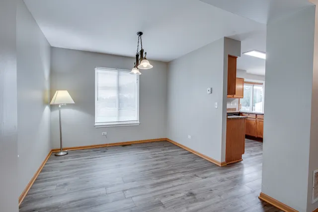 a view of an empty room with window and wooden floor