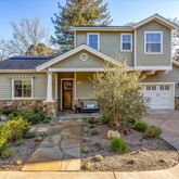 a view of a house with brick walls plants and large tree