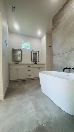 a spacious bathroom with a bathtub sink and mirror