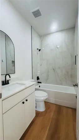 a bathroom with a bathtub shower sink vanity mirror and toilet