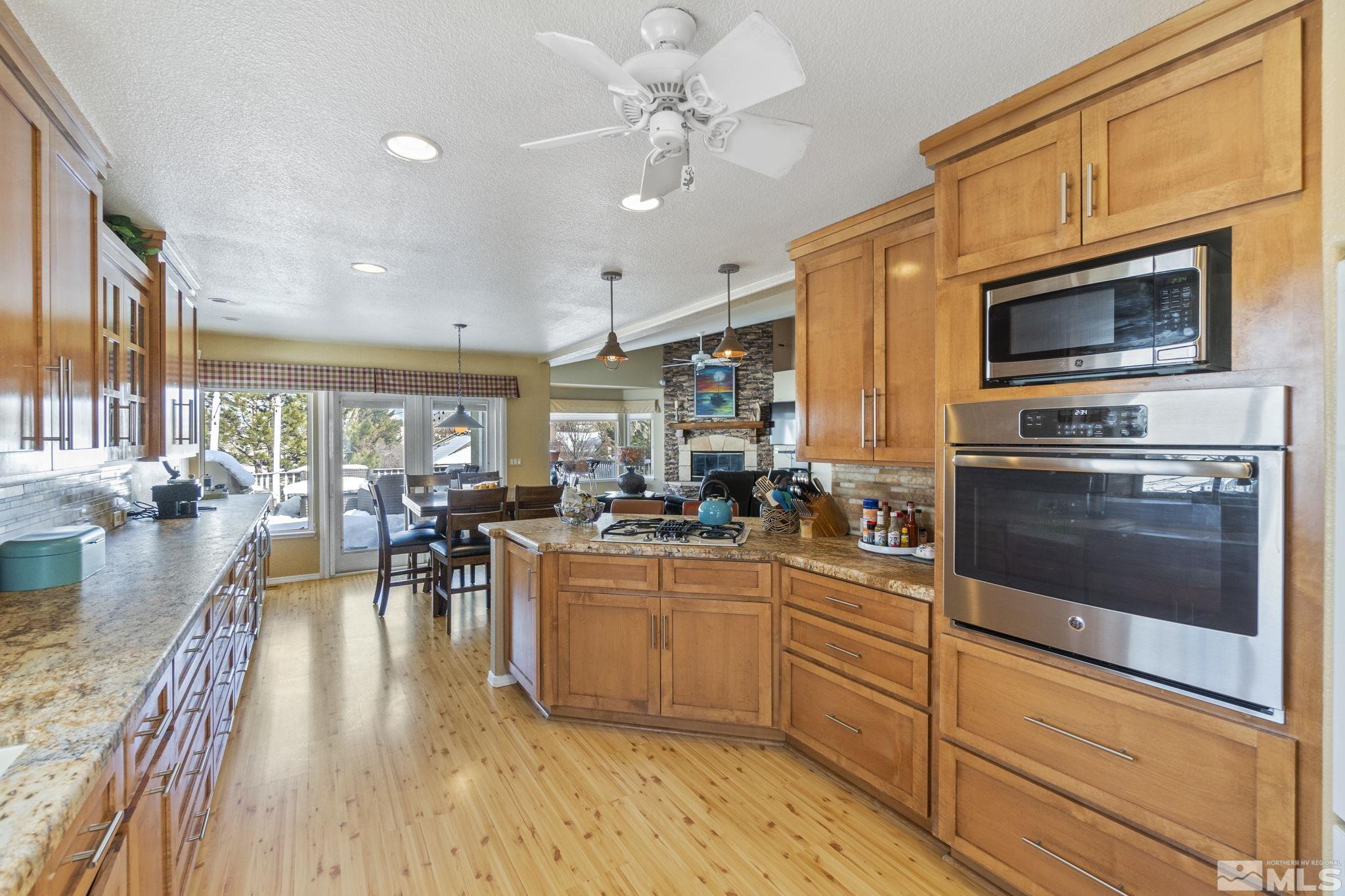 6075 Sunrise Meadows Loop Reno, NV 89519 - Photo 33 of 38 a kitchen with stainless steel appliances granite countertop a stove top oven a sink a dining table and chairs with wooden floor