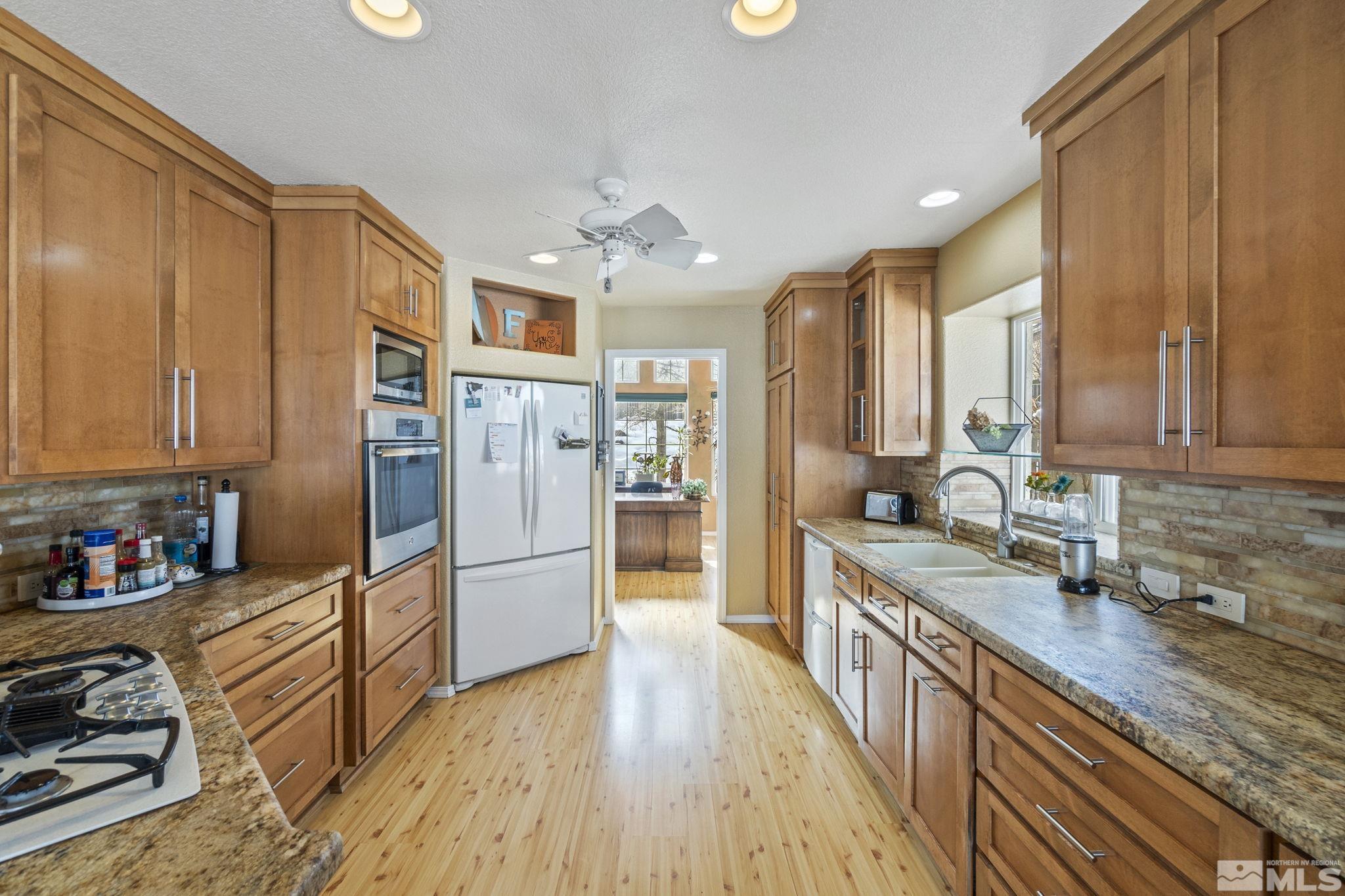 6075 Sunrise Meadows Loop Reno, NV 89519 - Photo 4 of 38 a kitchen with stainless steel appliances granite countertop a refrigerator a sink dishwasher stove and oven with wooden floor