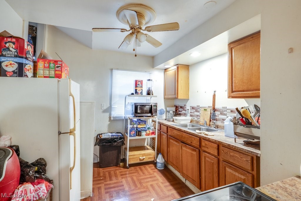 825 Rudyard Road Cleveland, OH 44110 - Photo 6 of 21 Kitchen with white refrigerator, light parquet flooring, sink, and ceiling fan