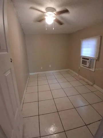 a view of an empty room and chandelier fan