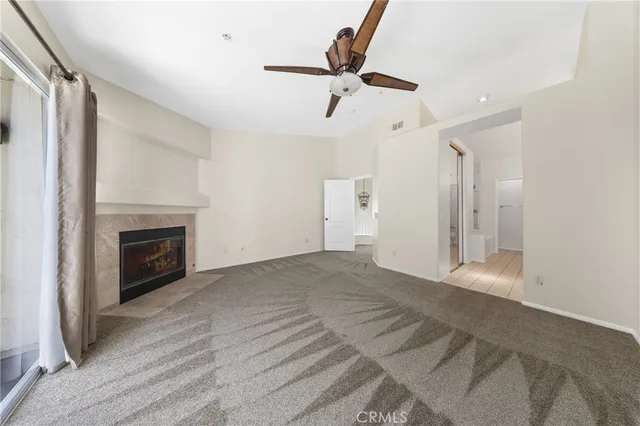 a view of a livingroom with a fireplace a ceiling fan and window