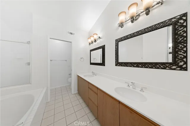 a bathroom with a double vanity sink a mirror and a bathtub