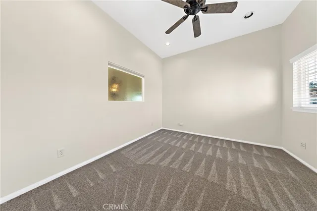 an empty room with windows and ceiling fan