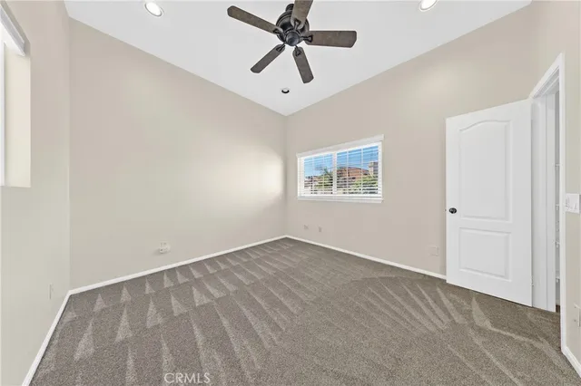 an empty room with windows and fan