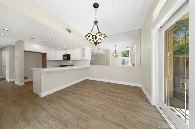 a view of a kitchen with kitchen island wooden floor center island and stainless steel appliances