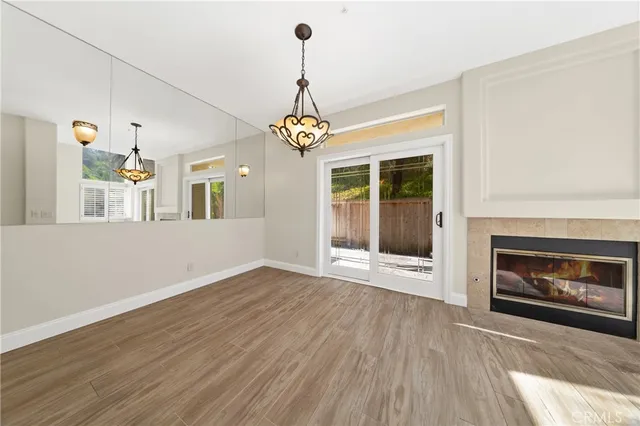 a view of an empty room with wooden floor fireplace and a window
