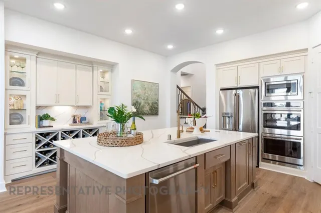 a kitchen with stainless steel appliances kitchen island granite countertop a sink and a refrigerator
