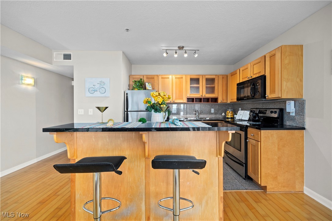 2222 Detroit Avenue, Unit 519 Cleveland, OH 44113 - Photo 3 of 30 Kitchen with a breakfast bar area, light hardwood flooring, decorative backsplash, and appliances with stainless steel finishes