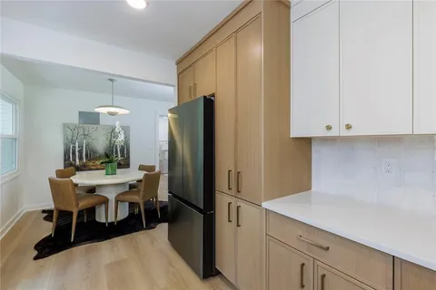 a kitchen with stainless steel appliances a refrigerator a sink a stove a dining table and chairs