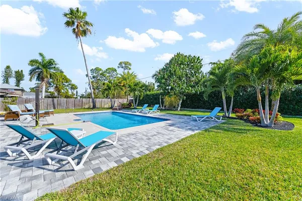 a view of a backyard with swimming pool and sitting area