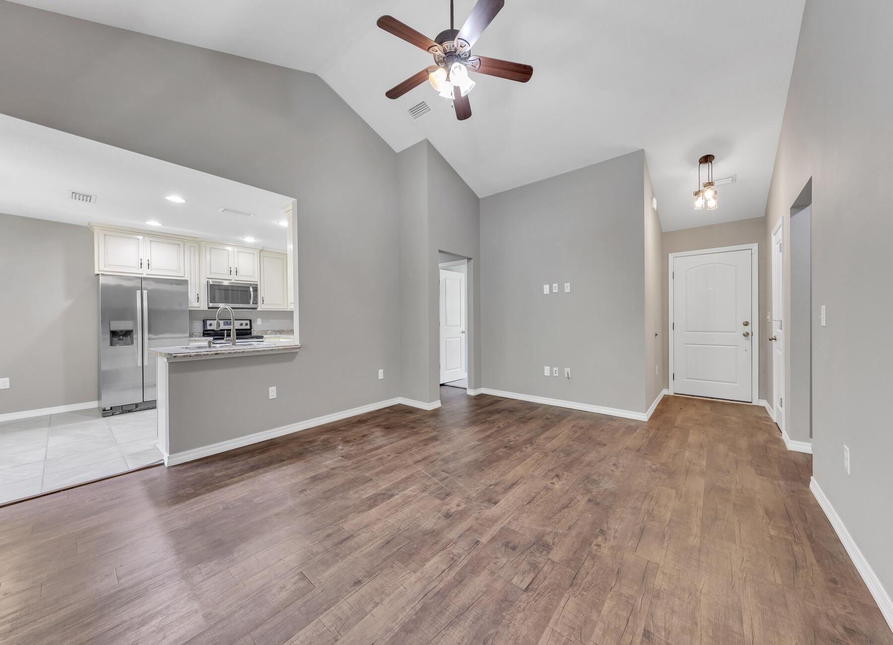 129 Fairway Drive Crestview, FL 32536 - Photo 4 of 30 a view of an empty room and kitchen with a sink wooden floor and a window