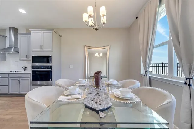 a dining room with wooden floor a chandelier a glass table and chairs