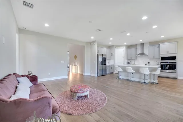 a living room with furniture and a dining table with wooden floor