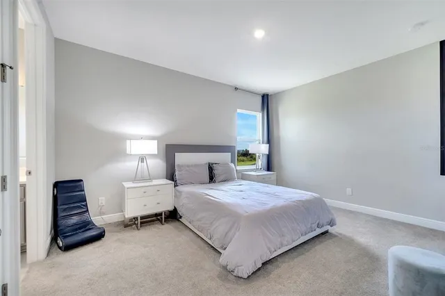 a bedroom with bed and a lamp on dresser