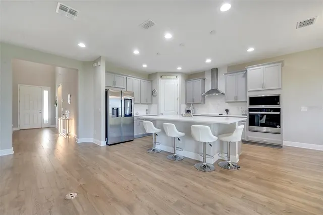 a living room with stainless steel appliances kitchen island granite countertop a table chairs a sink and a refrigerator