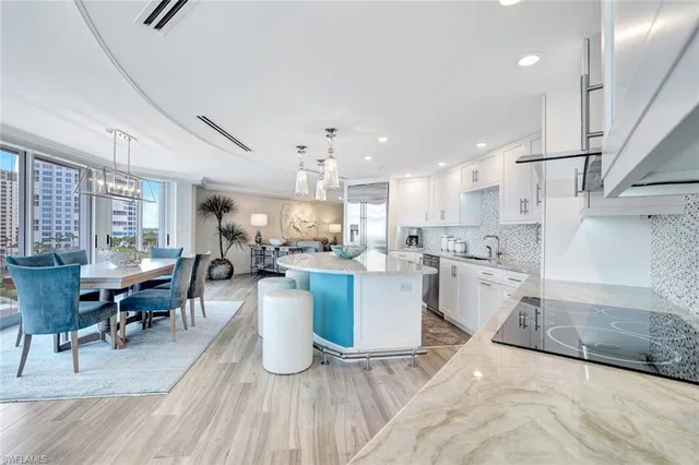 a living room with lots of furniture a dining table wooden floor and a view of kitchen