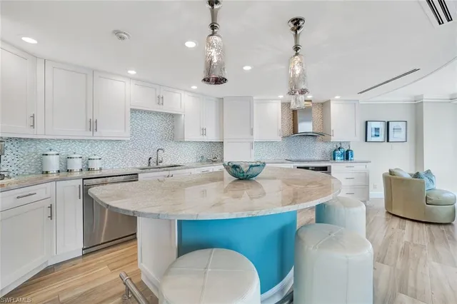 a kitchen with stainless steel appliances granite countertop a sink a stove a kitchen island with chairs and white cabinets