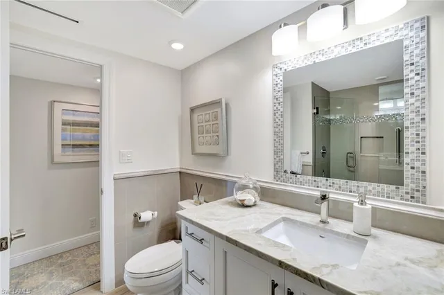 a bathroom with a granite countertop sink a toilet and a mirror