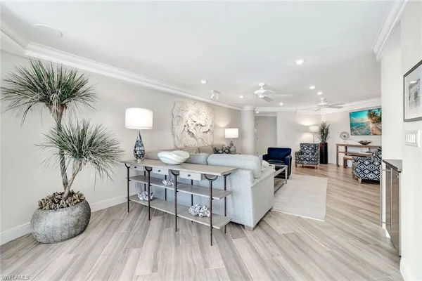 a living room with furniture a table kitchen and a potted plant