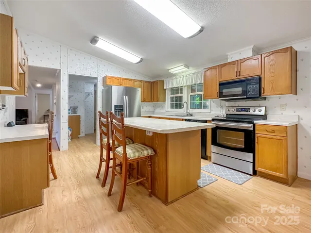 a kitchen with stainless steel appliances granite countertop a stove top oven a sink and a refrigerator