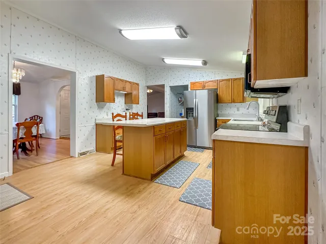 a large kitchen with stainless steel appliances granite countertop a stove refrigerator and a sink with cabinets