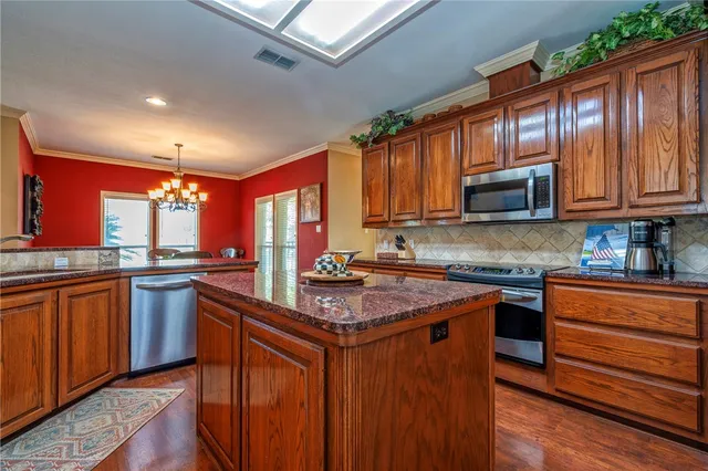 a kitchen with stainless steel appliances granite countertop wooden cabinets stove top oven and granite counter top