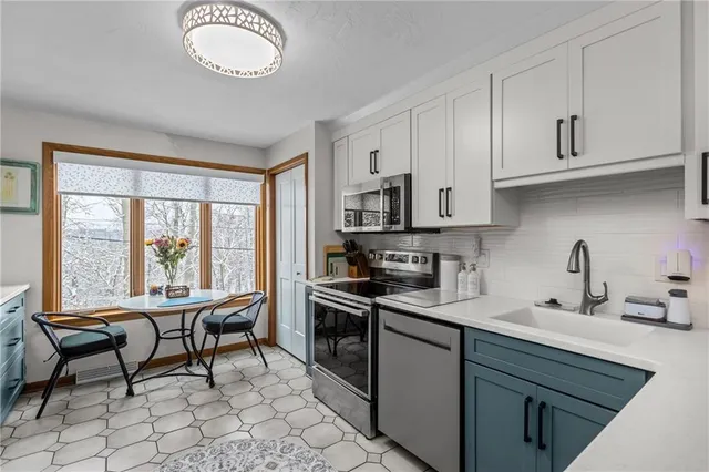 a kitchen with stainless steel appliances granite countertop a stove top oven a sink dishwasher a dining table and chairs with wooden floor