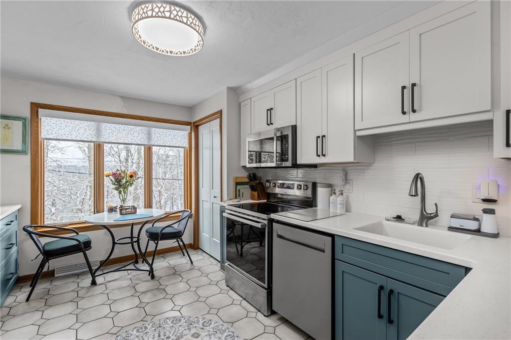 1104 West Ridge Road Allison Park, PA 15101 - Photo 8 of 32 a kitchen with stainless steel appliances granite countertop a stove top oven a sink dishwasher a dining table and chairs with wooden floor
