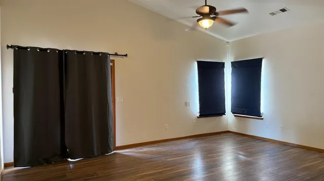an empty room with wooden floor closet and windows