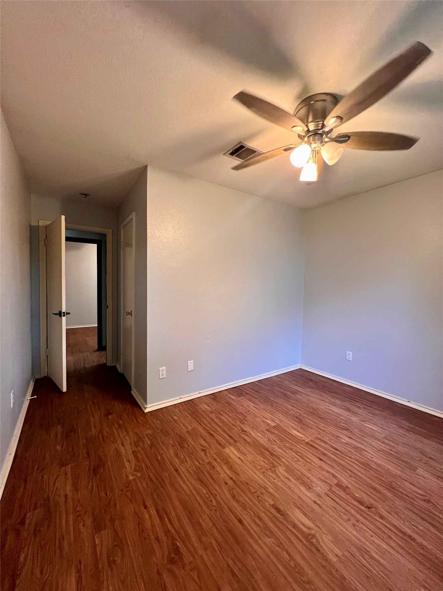 5404 China Berry Road Austin, TX 78744 - Photo 18 of 20 A comfortable bedroom with rich wood flooring and a refreshing ceiling fan.