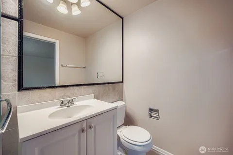 a bathroom with a toilet a sink a mirror and vanity